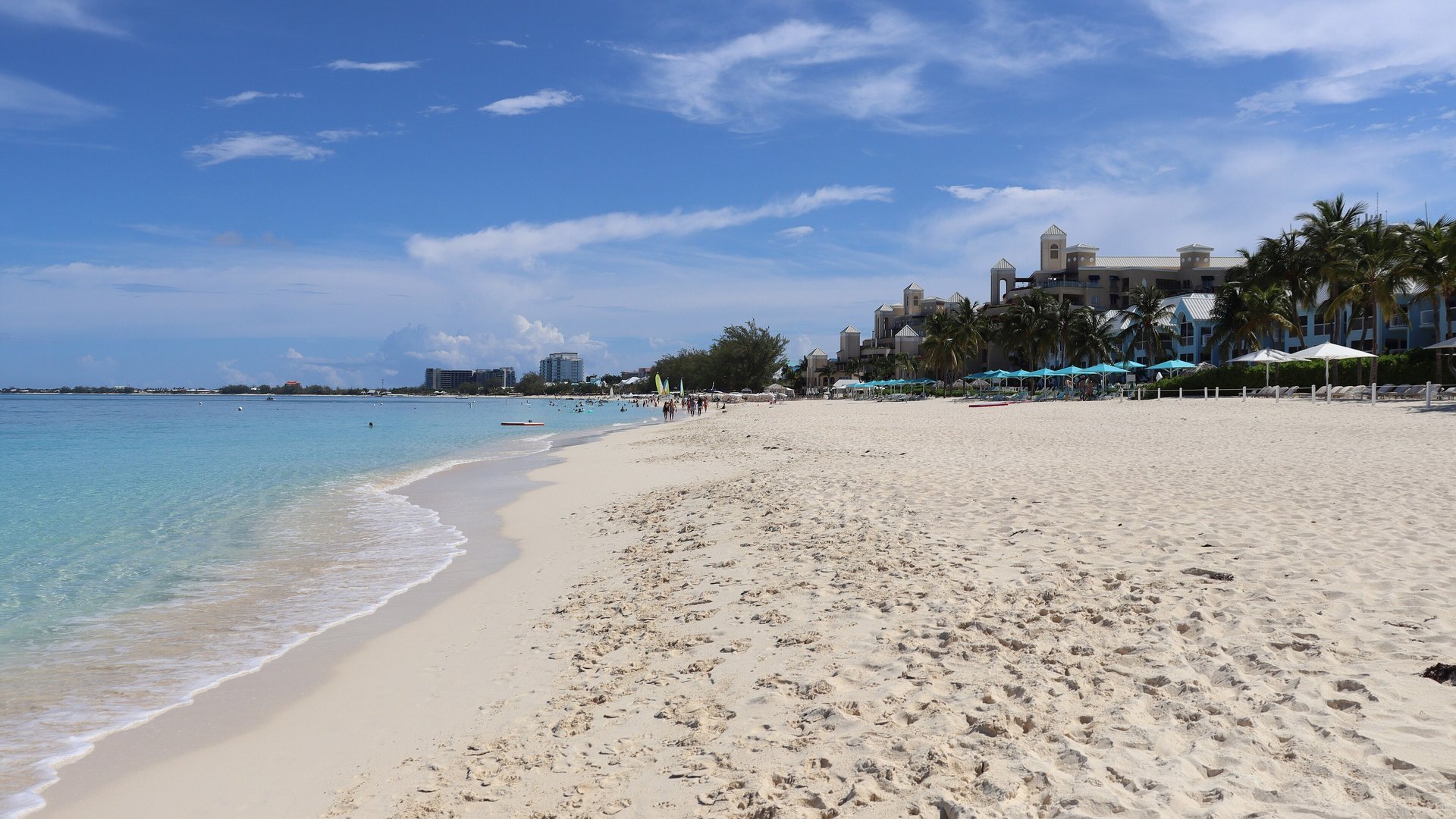 Calm turquoise water and soft white sand on a sunny day at Seven Mile Beach, Grand Cayman