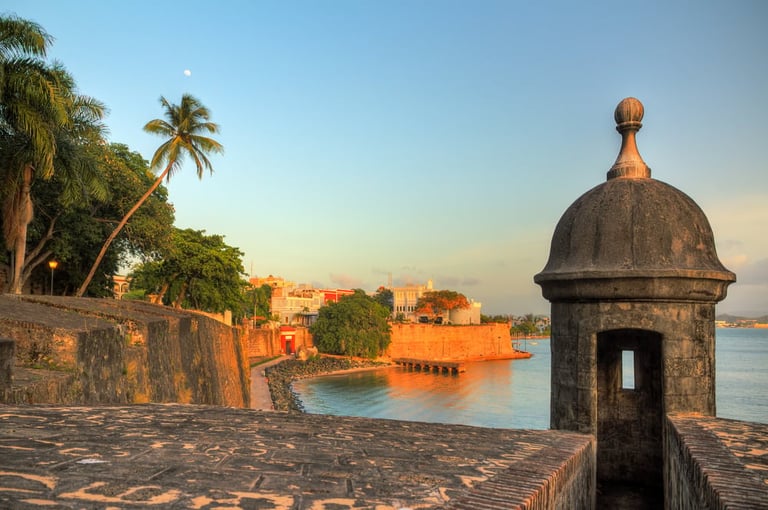 Historic stone fortress with domed watchtower overlooking waterfront and orange colonial buildings