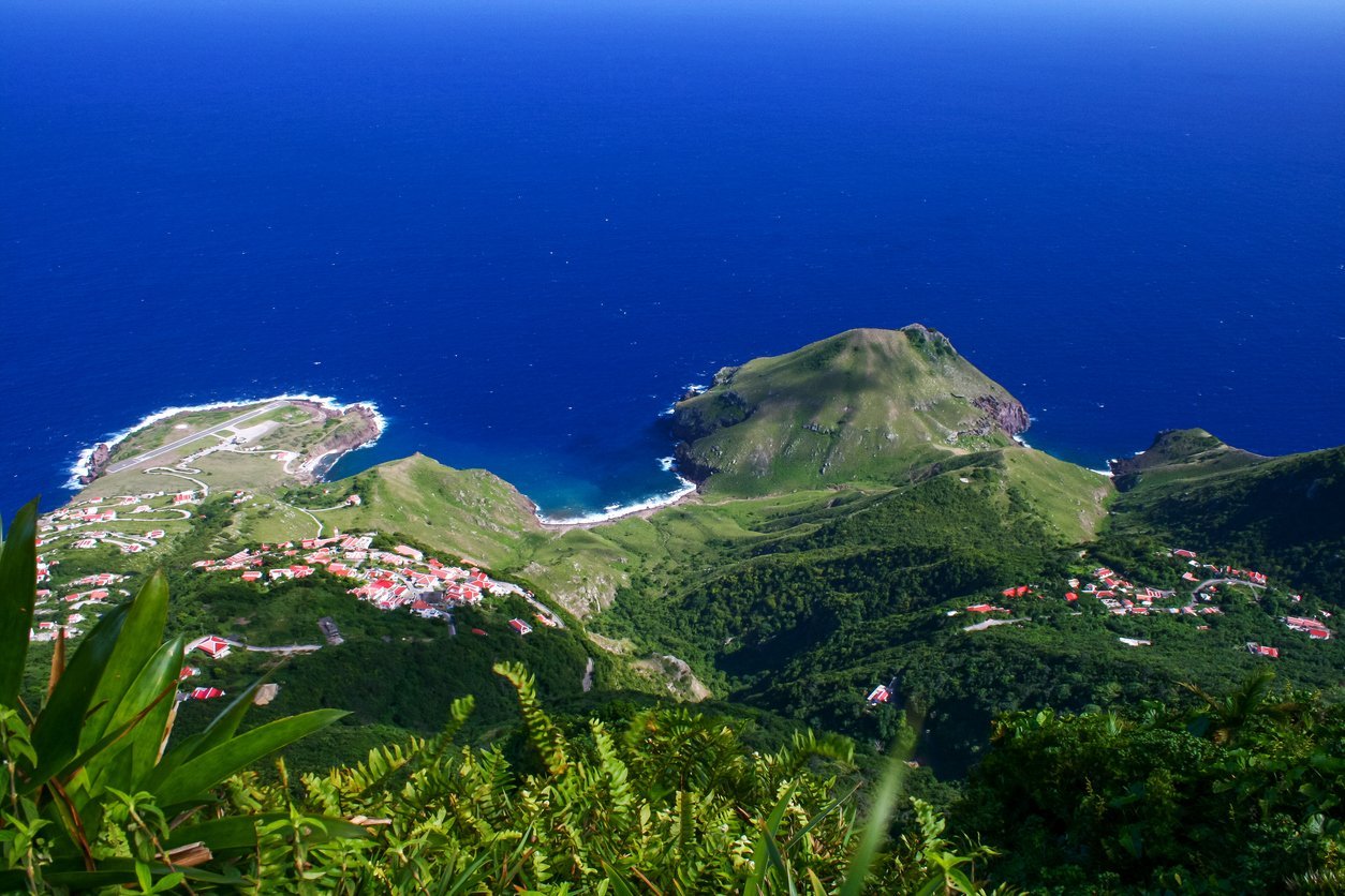 Aerial view of lush mountainous islands with vegetation and scattered buildings surrounded by deep blue ocean water