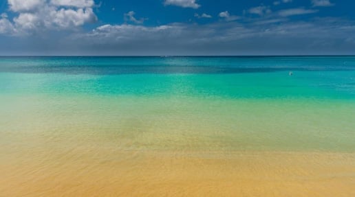 Tropical beach with turquoise water, white sand, and blue sky with white clouds
