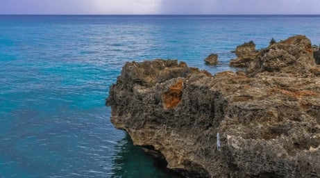 Rocky limestone cliffs overlooking turquoise Mediterranean sea with calm waters