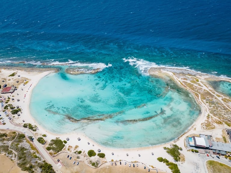 Aerial view of a turquoise lagoon with white sandy beach surrounded by crystal clear shallow waters and rocky outcrops