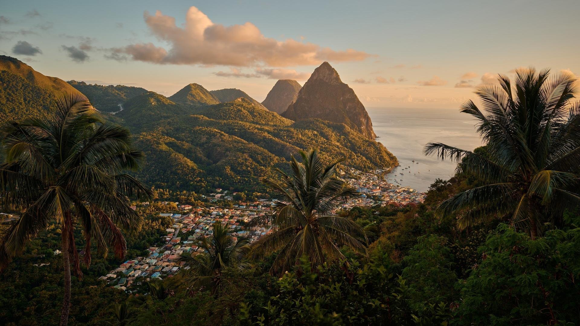 Sunset over Soufrière and the twin peaks of the Pitons, framed by palm trees, St. Lucia