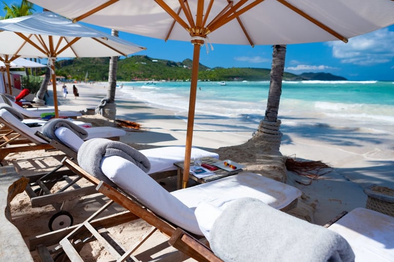Tropical beach with wooden umbrellas, loungers, and kayaks lined up on white sand by turquoise water
